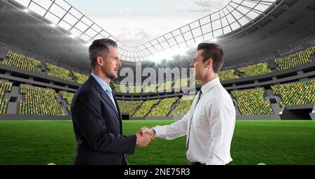 Composition of two businessmen shaking hands over sports stadium Stock Photo