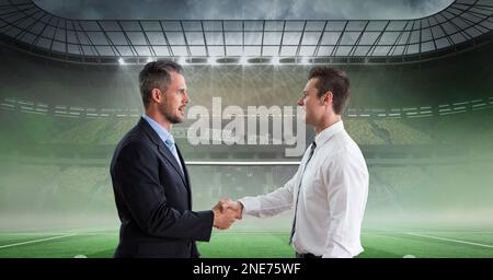 Composition of two businessmen shaking hands over sports stadium Stock Photo