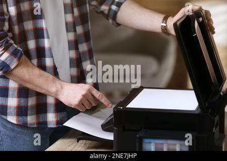 Man using modern multifunction printer in office, closeup Stock Photo