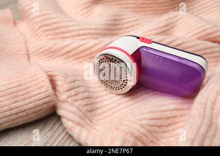 Modern fabric shaver for lint removing and sweater on wooden table Stock Photo