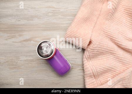 Modern fabric shaver for lint removing and sweater on wooden table, flat lay Stock Photo