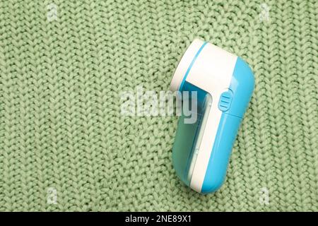 Modern fabric shaver for removing lint on green knitted cloth, top view Stock Photo
