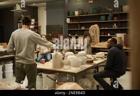Manager discussing designs with workers in a ceramics studio Stock Photo