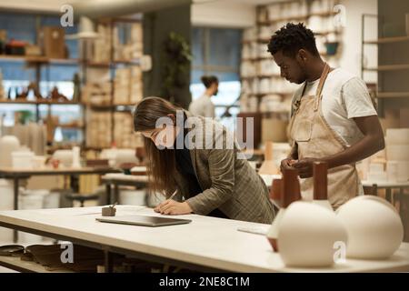 Ceramics studio manager working with a colleague at a table Stock Photo