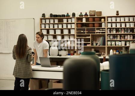 Ceramics studio workers talking together at a table Stock Photo