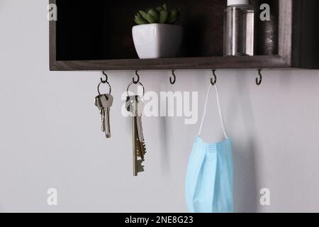 Wooden hanger for keys with different stuff on light grey wall Stock Photo