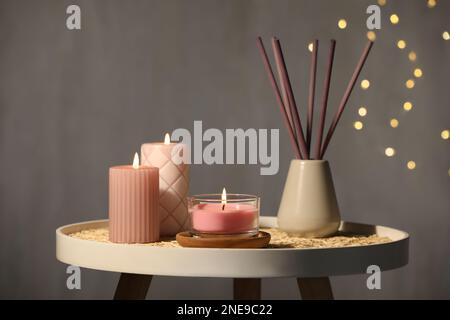 Burning candles and reed diffuser on table against grey background Stock Photo