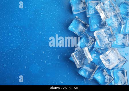 Ice cubes with water drops on light blue background, flat lay. Space for text Stock Photo
