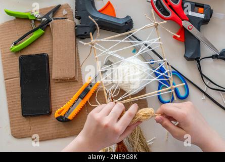 Scissors, electrical appliances, blanks, thread and rope are on table. Tools and materials for creative activity of designer. Stock Photo