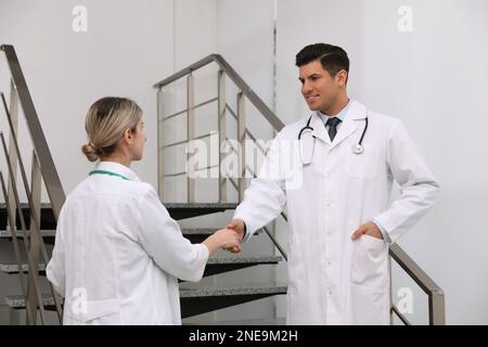 Doctors greeting with handshake on stairs in clinic Stock Photo