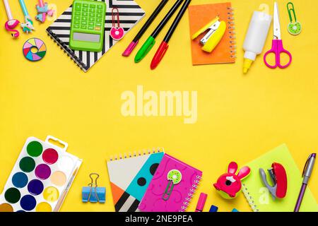 Back to school, education concept. Yellow backpack with school supplies - notebook, pens, ruler, calculator, scissors isolated on yellow background. Stock Photo