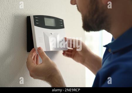 Man installing home security system on white wall in room, closeup Stock Photo