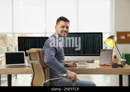 Happy programmer working at desk in office Stock Photo
