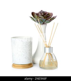Reed air freshener, aromatic candle and plant in vase on white background Stock Photo