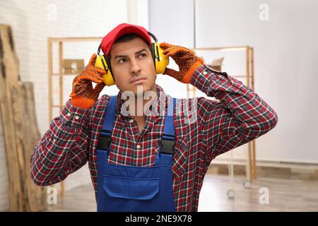 Worker wearing safety headphones indoors. Hearing protection device Stock Photo