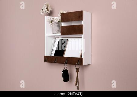Wooden hanger for keys with different stuff on color wall Stock Photo