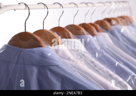 https://l450v.alamy.com/450v/2nea7b3/hangers-with-shirts-in-dry-cleaning-plastic-bags-on-rack-against-light-background-closeup-2nea7b3.jpg