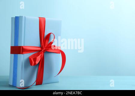 Different books tied with red ribbon on light blue wooden table, space for text Stock Photo