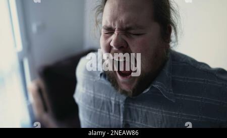 One overweight man suffering from back pain. A sedentary male person getting up from couch indoors having backache. Physical injury concept Stock Photo