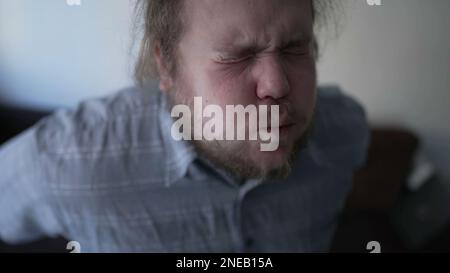 One fat guy having back pain when getting up from couch indoors. A sedentary overweight man suffering from physical injury backache. Person close up f Stock Photo