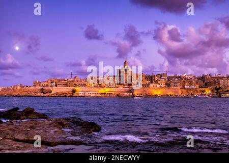 City skyline of Valletta at dusk in Malta, view from shore of the Manoel Island across Marsamxett Harbour. Stock Photo