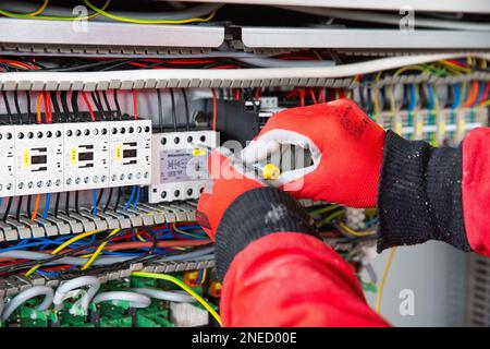 A closeup of hands in gloves doing electrical installation work. Stock Photo