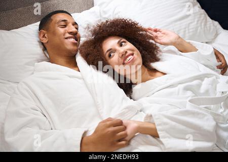 Cute multiracial woman lies on the shoulder of her husband Stock Photo
