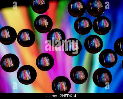 Colorful abstract pattern reflecting in black ringed glass drops Stock Photo