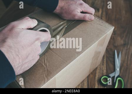 close-up of person sealing up shipping box with parcel tape, pruchase return and return of goods concept Stock Photo