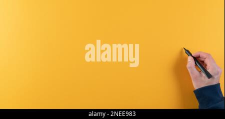 close-up of man writing on orange board with black felt tip pen or marker Stock Photo