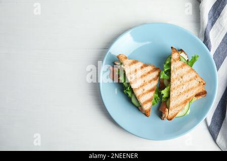 Blue plate with tasty sandwiches on white table, top view. Space for text Stock Photo