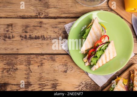 Green plate with tasty sandwiches on wooden table, flat lay. Space for text Stock Photo