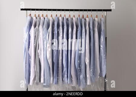 Premium Photo  Wooden hangers with clothes in dry cleaning bags closeup