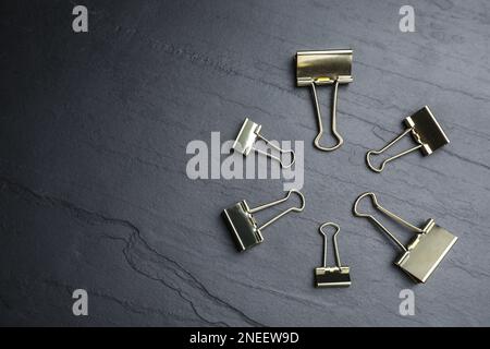 Binder clips on black background, flat lay. Space for text Stock Photo