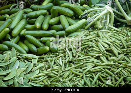 Heap of green vegetables like cucumber, broccoli, green peas and broad beans in a vendor cart Stock Photo