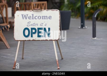 Metallic outdoor shop sign stating “Welcome, Enter it's OPEN”. Stock Photo