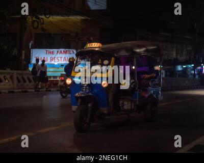 A rickshaw travelling through Bangkok at night. Stock Photo