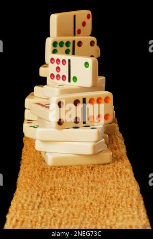 Dominoes with colorful dots are stacked high in a pile on a coco mat material. Isolate image has room for text. Tiles are clean and new. Stock Photo