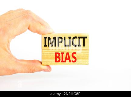 Implicit bias symbol. Concept words Implicit bias on wooden block. Beautiful white table white background. Businessman hand. Business psychology impli Stock Photo