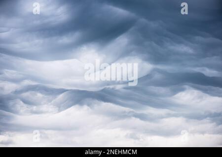 Fascinated wavy ridges of the rare asperitas clouds with dark blue textures and undulating ripples and waves of light. Stock Photo