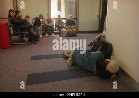 Travelers waiting to board an American Airlines flight relax in the terminal as a fellow traveler catches up on some sleep at Los Angeles International Airport on the ninth day of the American airlines pilot sick out on Saturday, Feb. 13, 1999. American cancelled 845 flights for Saturday and 209 for Sunday. (AP Photo/Chris Pizzello)
