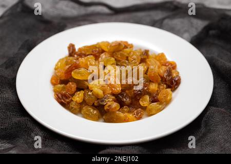 Yellow golden raisins in white ceramic plate on ceramic Stock Photo