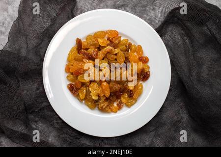 Yellow golden raisins in white ceramic plate on ceramic Stock Photo