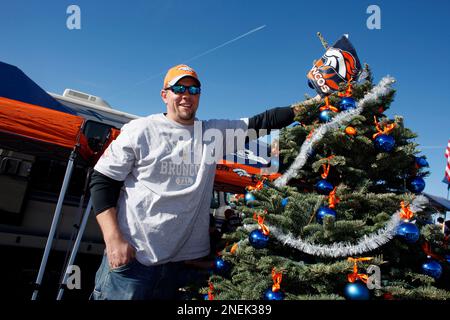 Jake Denooy of Fort Collins, Colo., places a Denver Broncos flag to top off  a Christmas tree while he tailgates before the Oakland Raiders face the  Broncos in the first quarter of