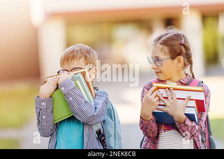 Girl and boy in glasses standing with books in their hands. Stock Photo