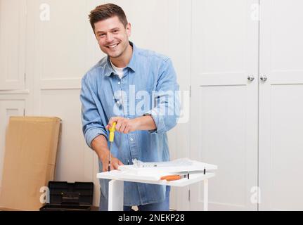 Portrait Of Man Putting Together Self Assembly Furniture At Home Stock Photo