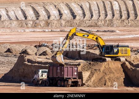 A heavy duty excavator loads a container truck with hazardous uranium tailings at the UMTRA remediation project, Moab, Utah. Stock Photo