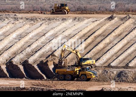 A heavy duty excavator loads a dump truck with hazardous uranium tailings at the UMTRA remediation project, Moab, Utah. Stock Photo