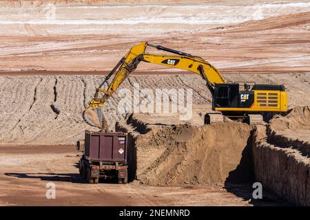 A heavy duty excavator loads a container truck with hazardous uranium tailings at the UMTRA remediation project, Moab, Utah. Stock Photo