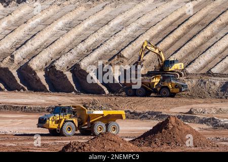 A heavy duty excavator loads a dump truck with hazardous uranium tailings at the UMTRA remediation project, Moab, Utah. Stock Photo